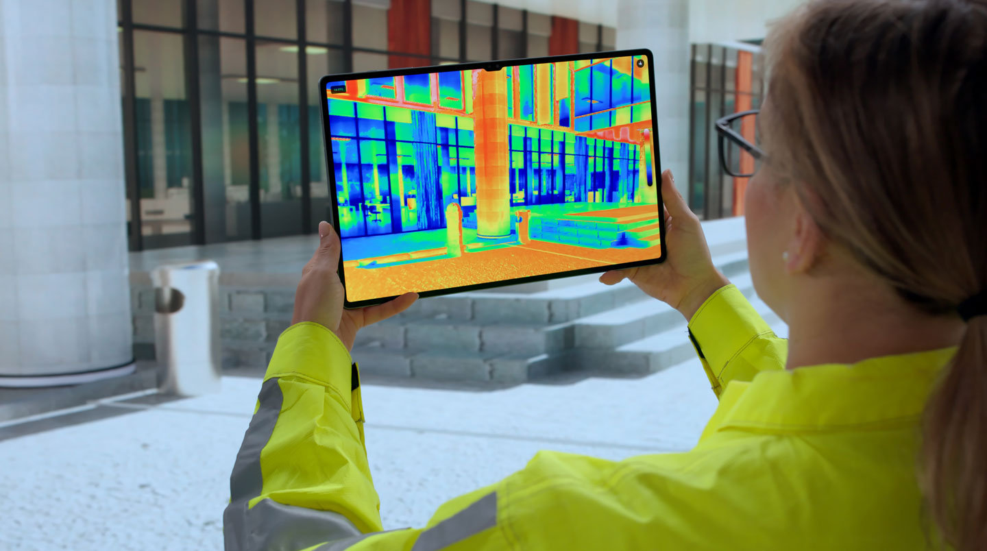 Un expert en thermique effectuant une inspection visuelle de l'isolation d'un immeuble en copropriété, équipé d'instruments de mesure, en présence d'un gestionnaire